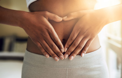 woman holding hands in heart shape on stomach