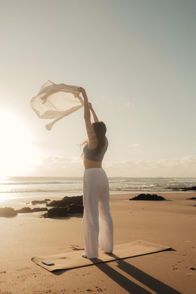 woman on beach holding scarf in the air
