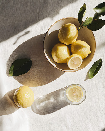 lemons in a bowl with lemon water on table